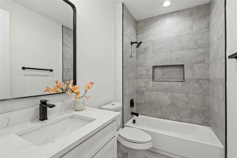 Full bathroom featuring tiled shower / bath combo, toilet, and vanity