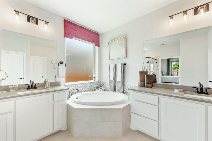 Master bathroom with dual vanities, soaking tub, mosaic tile surround, and dual mirrors with vanity lighting Master bathroom with dual vanities, soaking tub, mosaic tile surround, and dual mirrors with vanity lighting