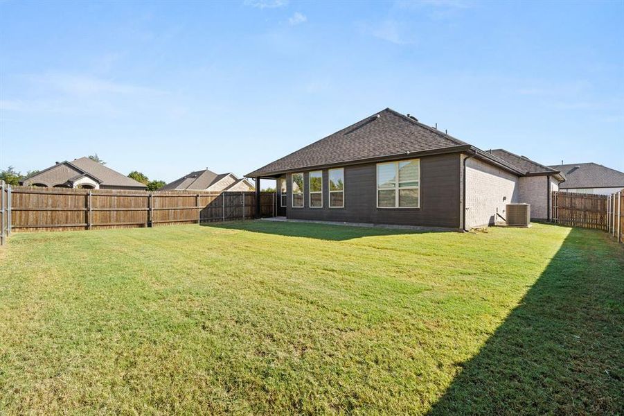 Rear view of property with a fenced backyard, a shingled roof, brick siding, and a patio Rear view of property with a fenced backyard, a shingled roof, brick siding, and a patio