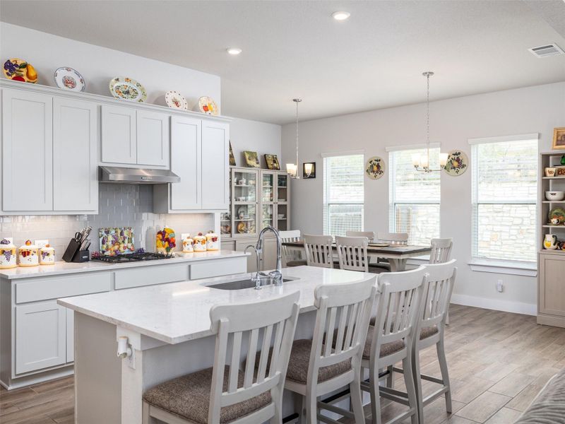 Kitchen featuring light wood finished floors, light stone counters, a breakfast bar, and backsplash