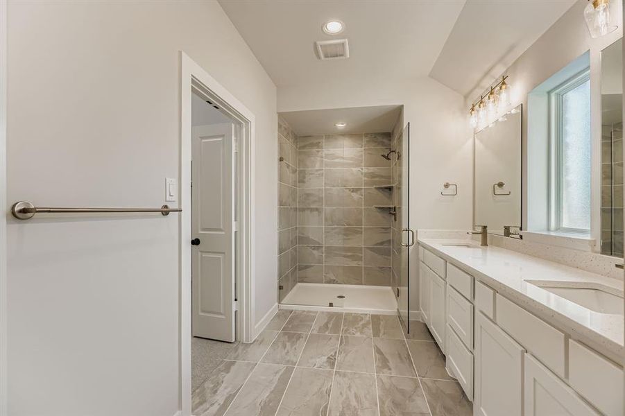 Full bathroom featuring double vanity, a shower stall, marble look tile flooring, and recessed lighting