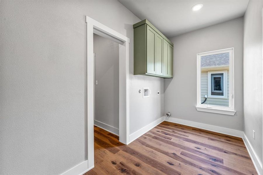 Laundry room featuring electric dryer hookup, dark wood-style flooring, cabinet space, and washer hookup Laundry room featuring electric dryer hookup, dark wood-style flooring, cabinet space, and washer hookup