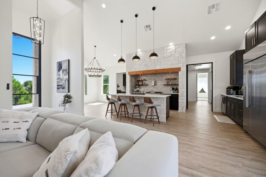 Soaring ceilings and light wood floors connect the airy living space to the kitchen.