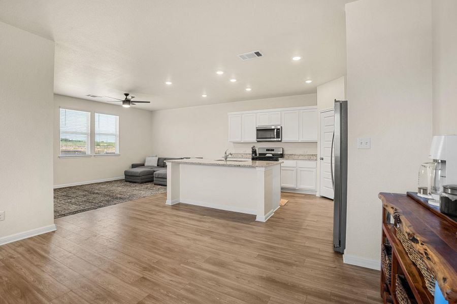 An open concept living area boasts a central kitchen island and durable plank flooring.