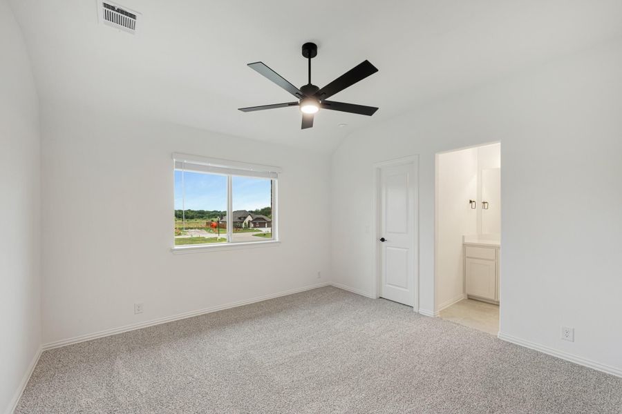 Empty bedroom with carpet, black ceiling fan, and doorway leading to an ensuite bathroom