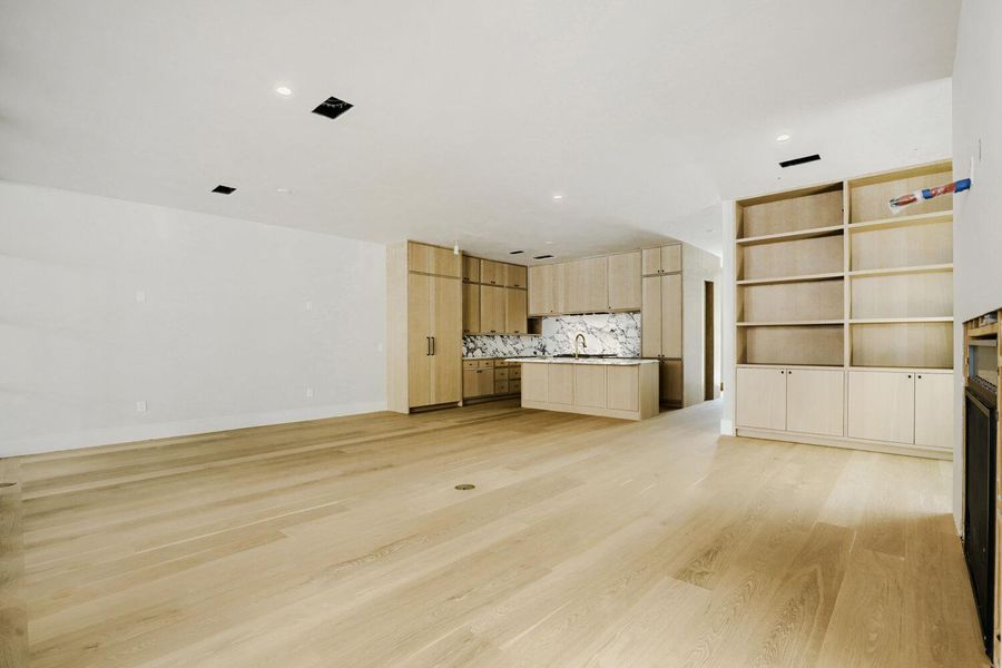 Blonde hardwood floors extend across this versatile open-concept living space with a modern kitchen.