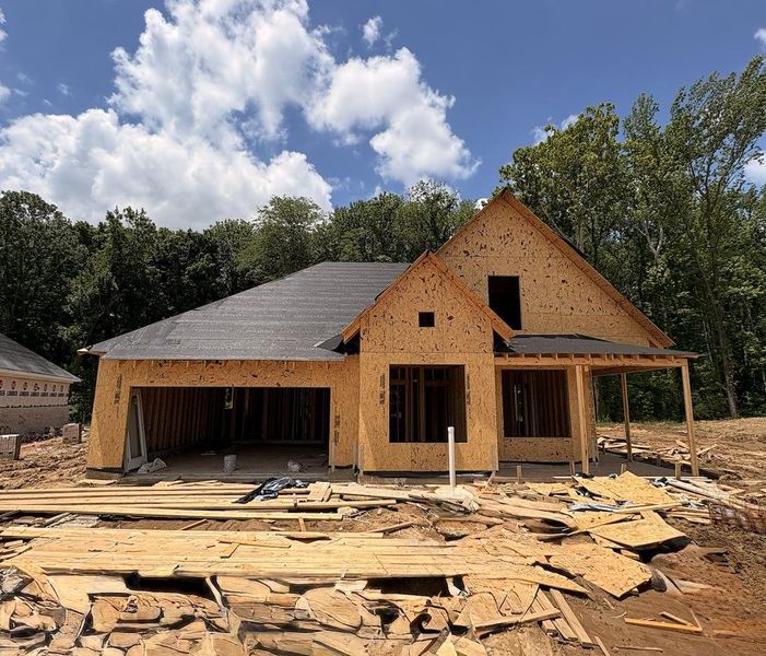New construction framing with sheathing, a two-car garage, and a covered porch entry New construction framing with sheathing, a two-car garage, and a covered porch entry