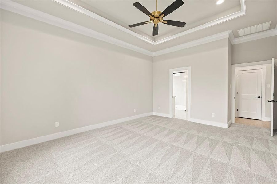 Spare room with a tray ceiling, light carpet, ornamental molding, and a ceiling fan Spare room with a tray ceiling, light carpet, ornamental molding, and a ceiling fan