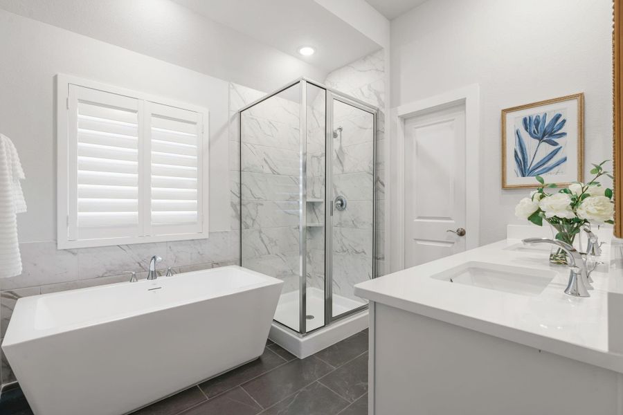 Primary bathroom creates a spa like feel with soaking tub, shower, and double sinks - door leads to toilet area