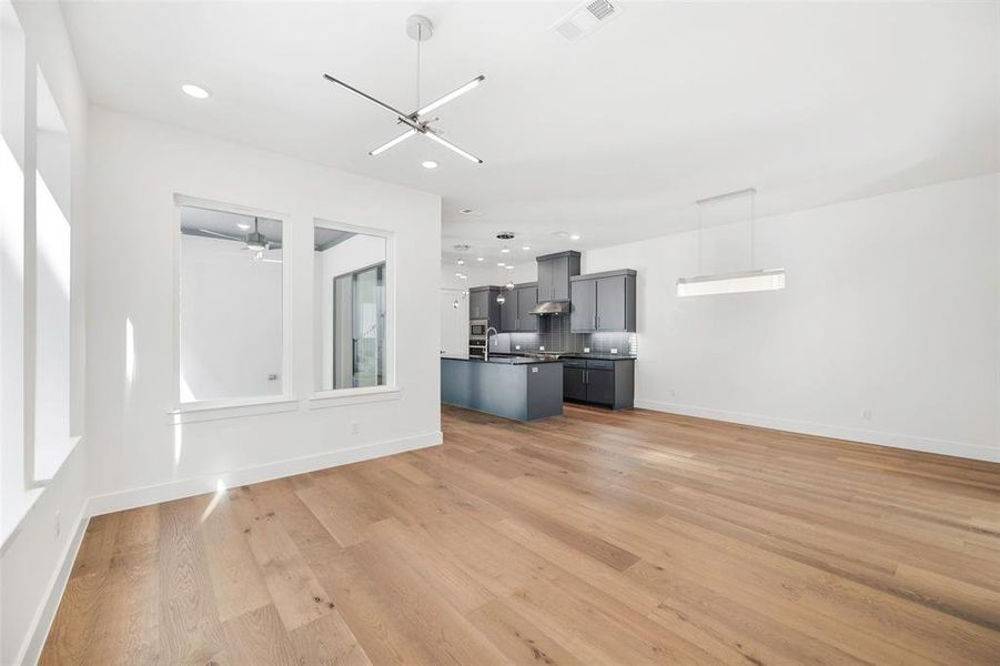 Unfurnished living room featuring light wood-style flooring, visible vents, baseboards, and recessed lighting