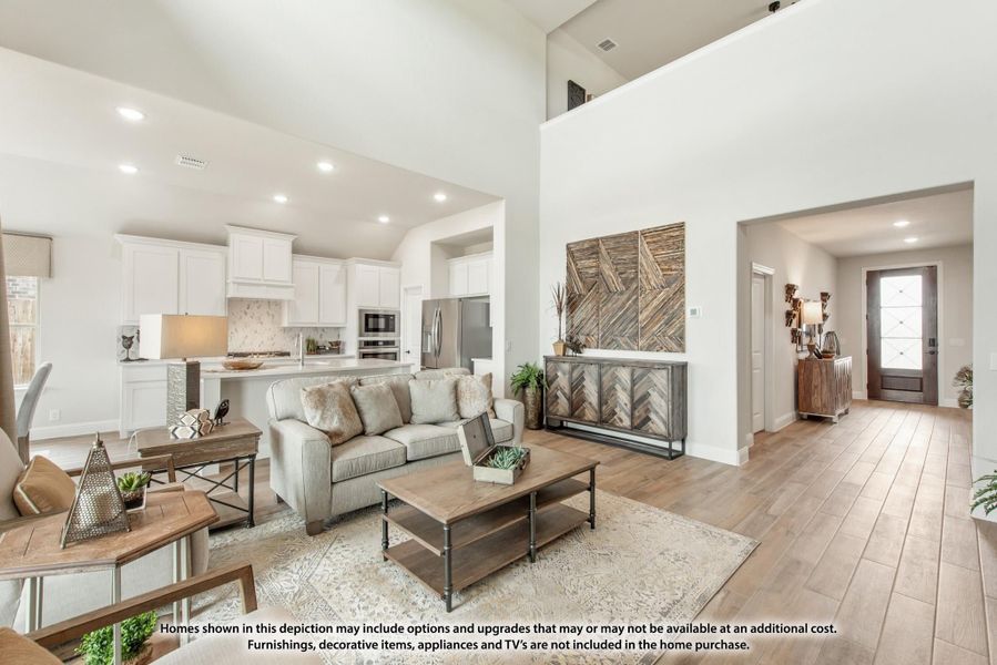 Open-concept living room and kitchen with vaulted ceilings, hardwood floors, and white cabinets