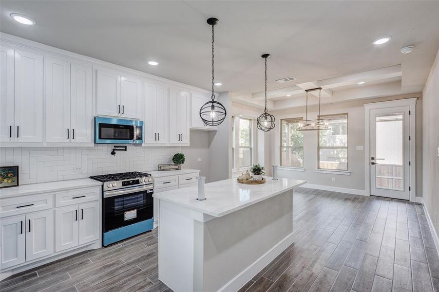 Kitchen featuring stainless steel appliances, wood tiled floors, recessed lighting, white cabinetry, and decorative backsplash