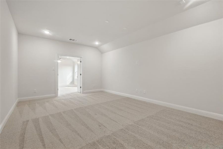 Unfurnished room featuring baseboards, visible vents, light carpet, and lofted ceiling Unfurnished room featuring baseboards, visible vents, light carpet, and lofted ceiling