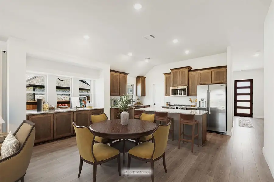 Open-concept kitchen and dining area with dark wood cabinets, granite counters, stainless appliances, and round dining table with yellow chairs. Open-concept kitchen and dining area with dark wood cabinets, granite counters, stainless appliances, and round dining table with yellow chairs.