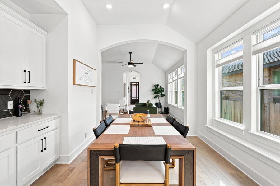 Hardwood floors and an arched transition define this open dining area adjacent to the kitchen.