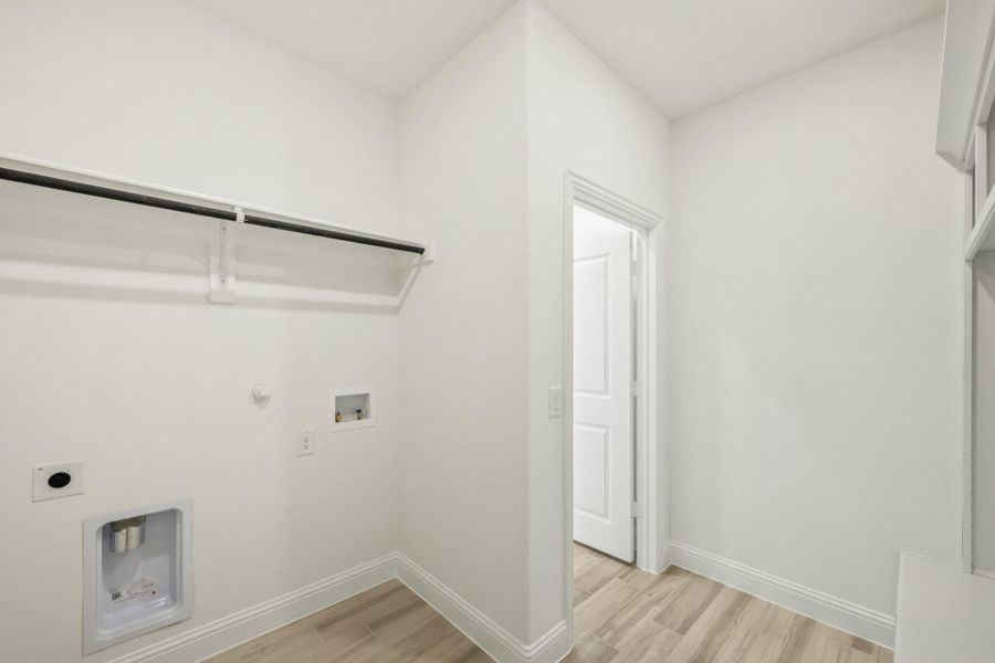 Laundry room with hanging rod, washer and dryer hookups, and light wood floors Laundry room with hanging rod, washer and dryer hookups, and light wood floors