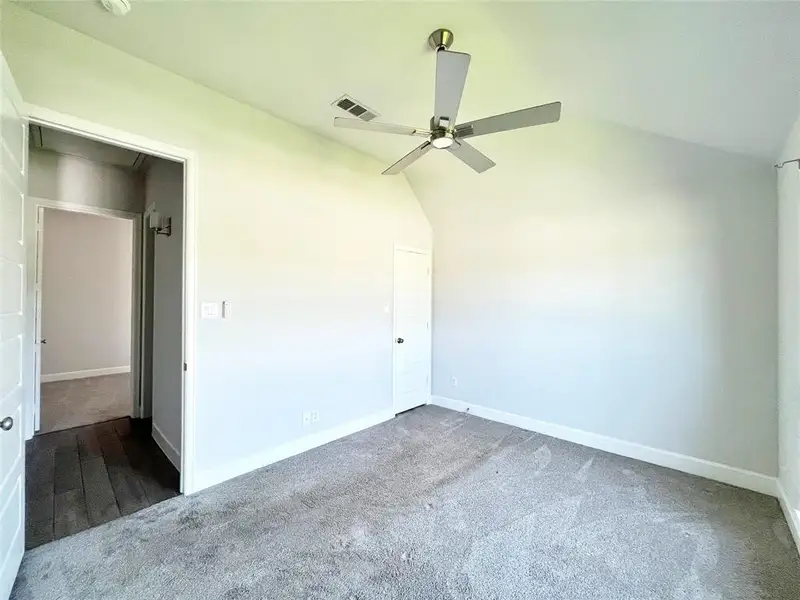 Unfurnished bedroom with vaulted ceiling, carpet, and ceiling fan Unfurnished bedroom with vaulted ceiling, carpet, and ceiling fan