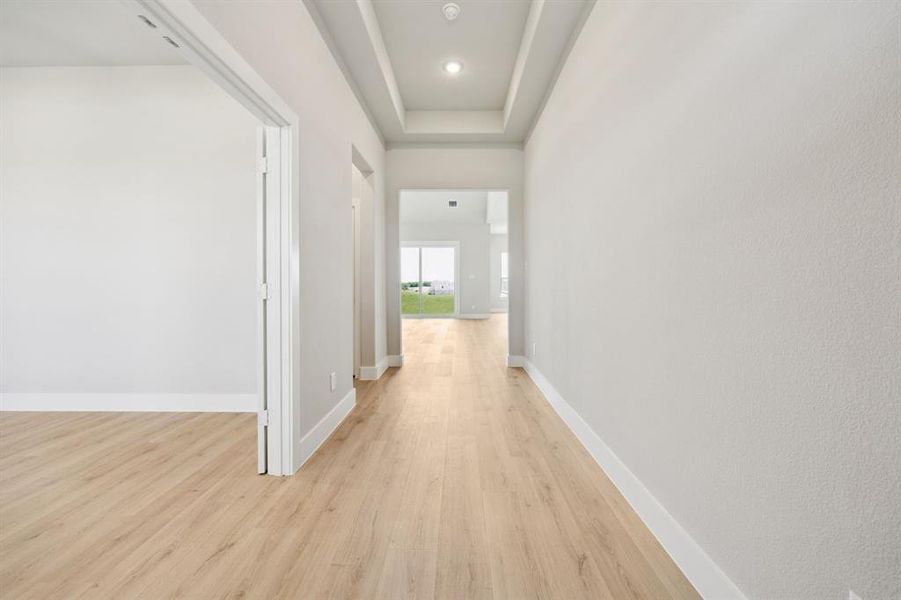 Corridor with light wood finished floors and a raised ceiling