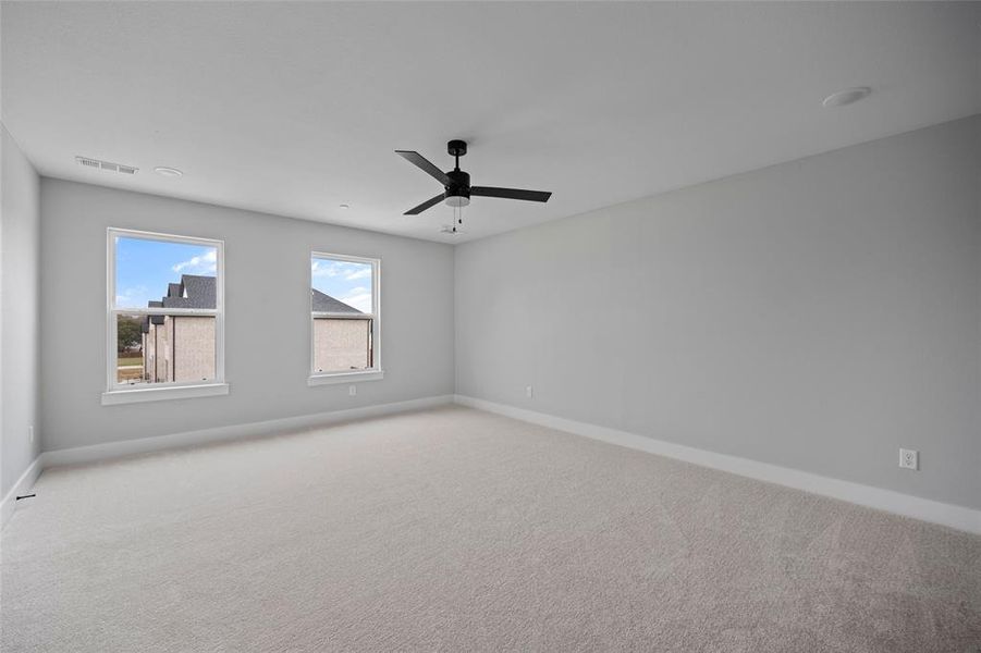 Carpeted empty room with visible vents, baseboards, and ceiling fan