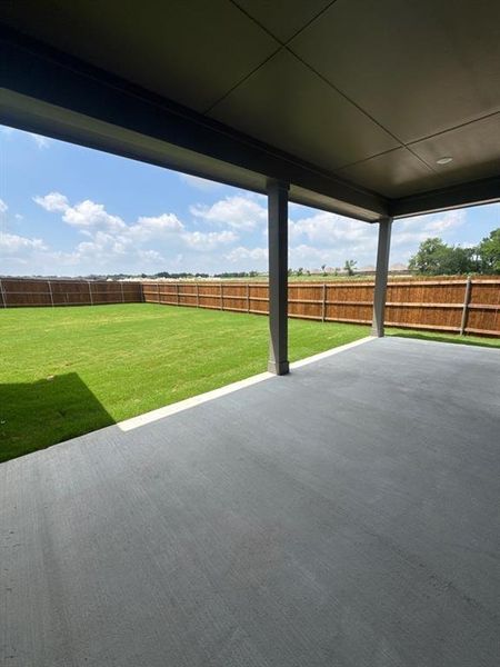 Expansive covered patio with a smooth concrete surface, supported by sturdy columns