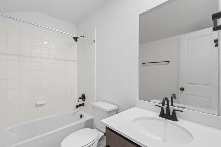 The secondary bath features tile flooring, white cabinetry and light countertops and a shower/tub combo. Perfect for accommodating any visiting family and friends.