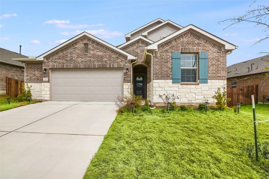 Single story home featuring stone siding, a front yard, fence, and driveway