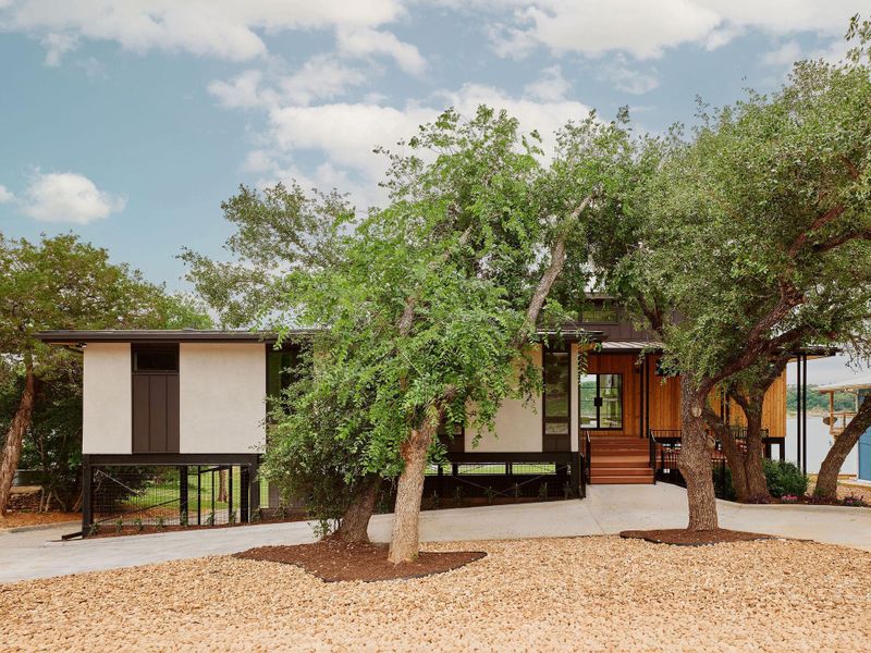 Modern architecture featuring a raised foundation, a concrete driveway, and natural wood siding accents