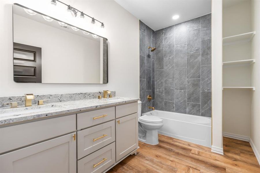 Hall bathroom with tiled shower, open shelving, and dual sinks Hall bathroom with tiled shower, open shelving, and dual sinks