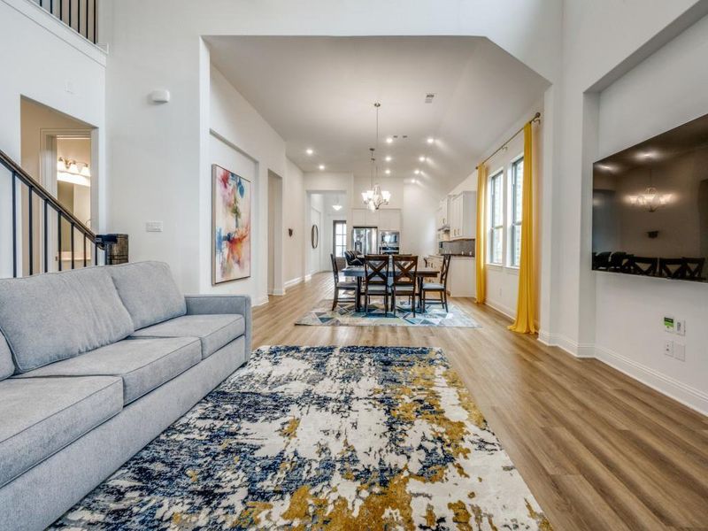 Living area with baseboards, an inviting chandelier, stairway, and light wood-type flooring