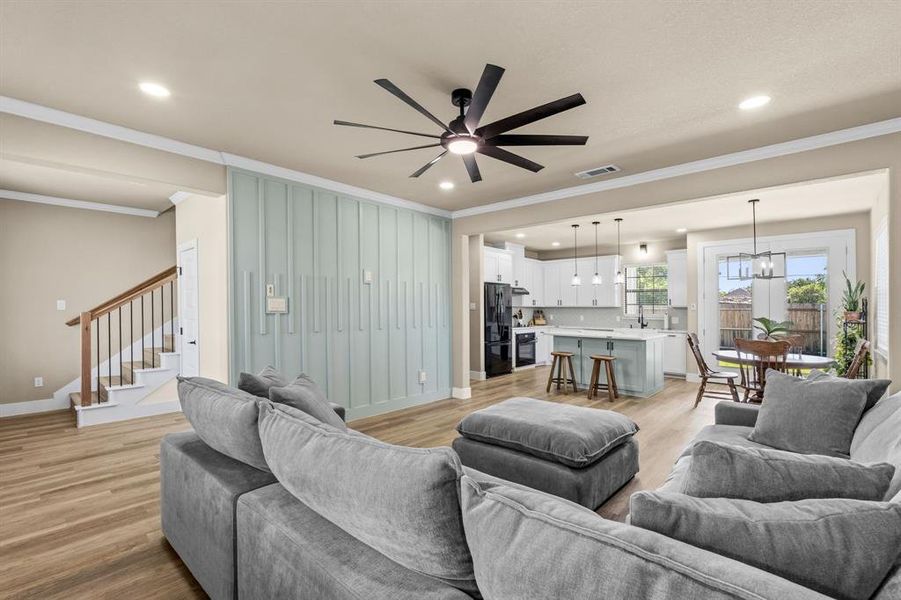 Open-concept living area with wood-finish flooring and a decorative accent wall featuring vertical paneling