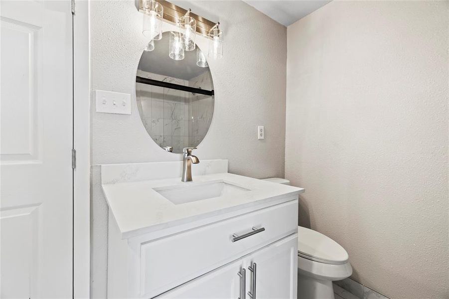 Bathroom featuring a textured wall, a stall shower, and vanity