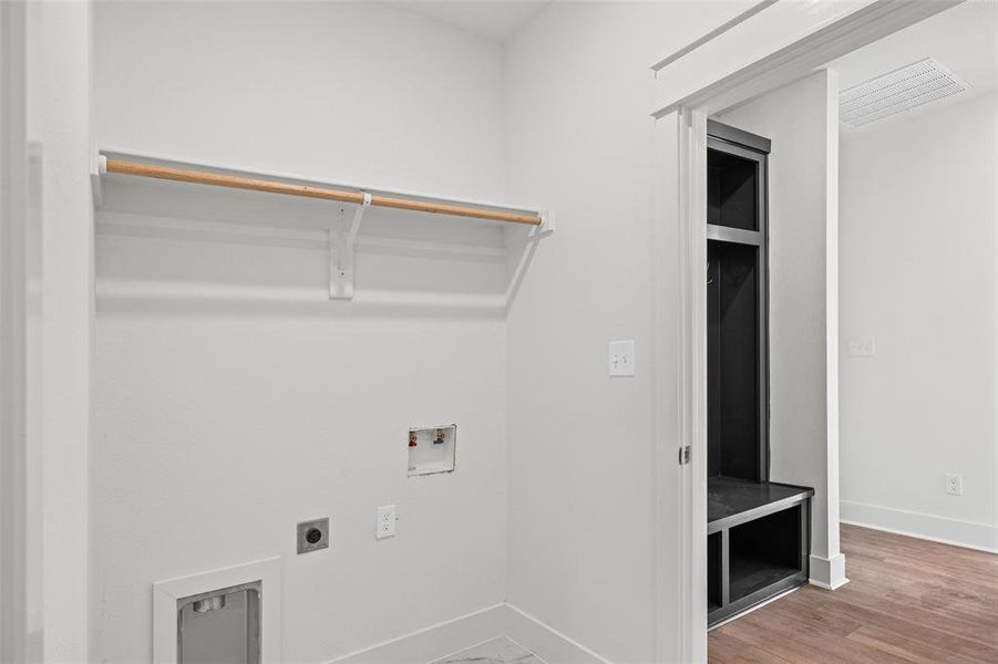 Dedicated laundry area featuring a clothing rod, utility hookups, and a floor vent