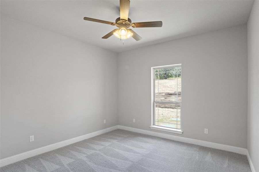 Empty room featuring ceiling fan, plenty of natural light, and carpet flooring