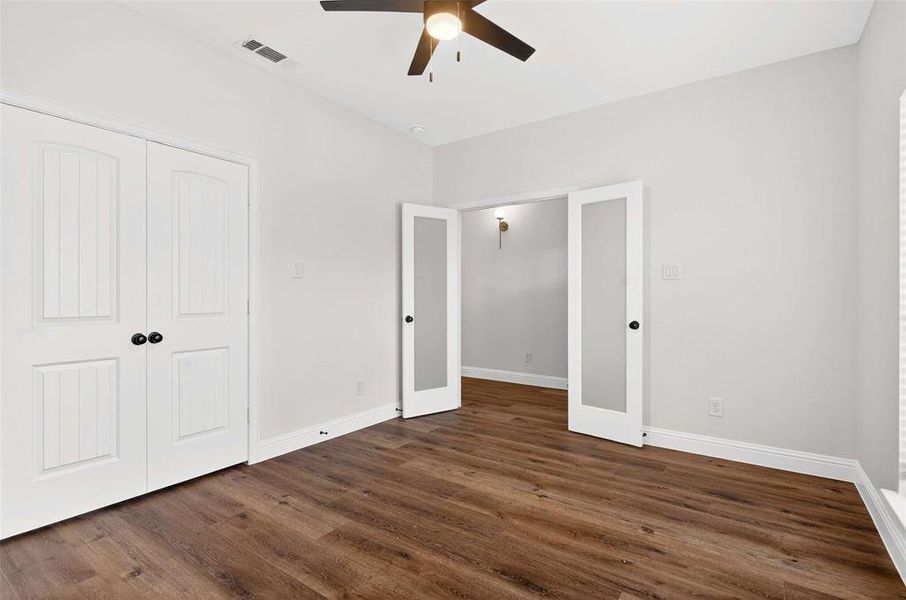 Unfurnished bedroom with ceiling fan, dark wood-style flooring, and a closet