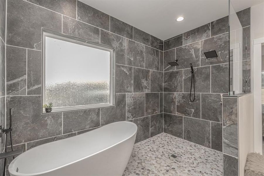Bathroom featuring a freestanding tub, walk in shower, recessed lighting, and tile walls