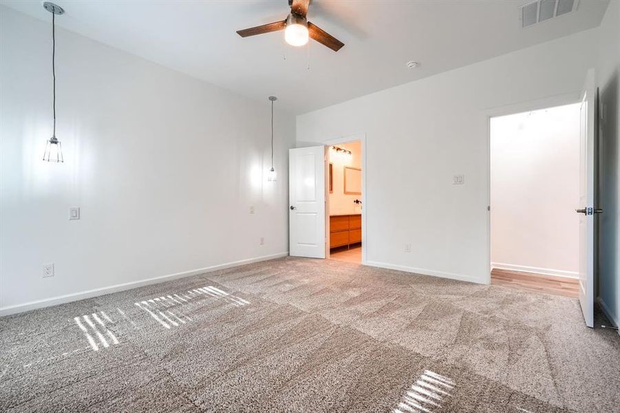 Unfurnished bedroom featuring carpet flooring, a ceiling fan, and ensuite bath