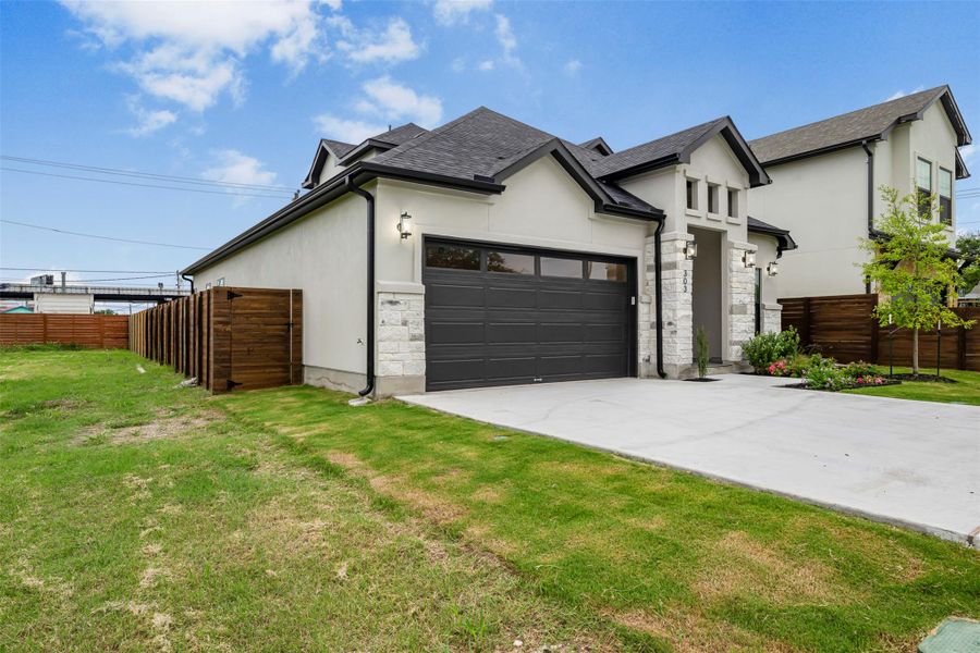 Front view of the property showcasing stucco and stone siding, a concrete driveway, and a shingled roof. Front view of the property showcasing stucco and stone siding, a concrete driveway, and a shingled roof.
