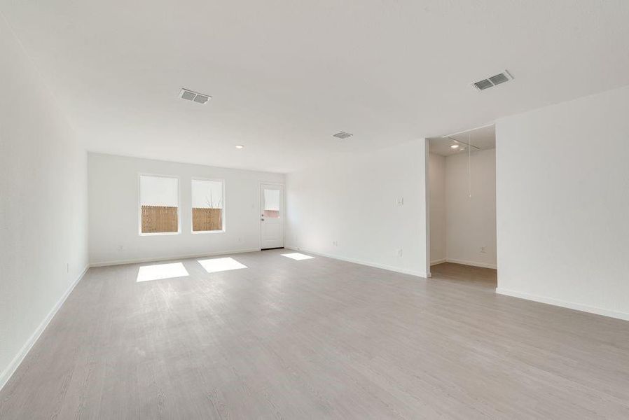 Empty room with light wood finished floors, attic access, visible vents, and baseboards