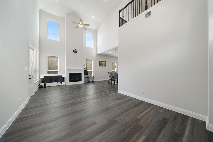 Unfurnished living room featuring high vaulted ceiling, ceiling fan, and dark wood-type flooring