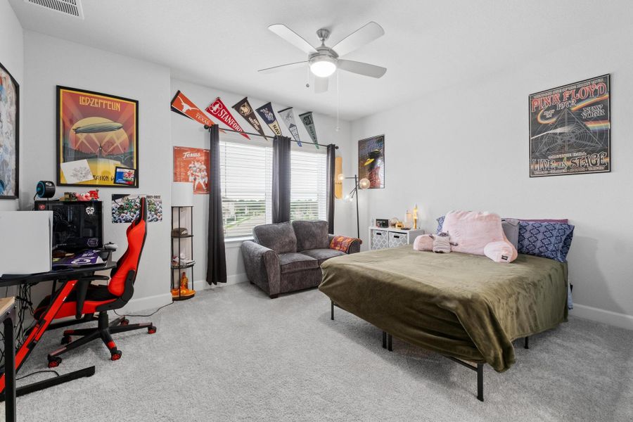 Carpeted bedroom featuring baseboards, a ceiling fan, and visible vents Carpeted bedroom featuring baseboards, a ceiling fan, and visible vents