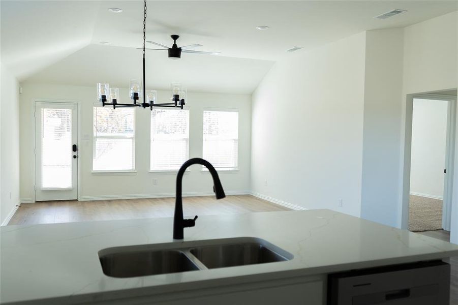 Kitchen with dishwasher, vaulted ceiling, light stone countertops, light wood finished floors, and open floor plan
