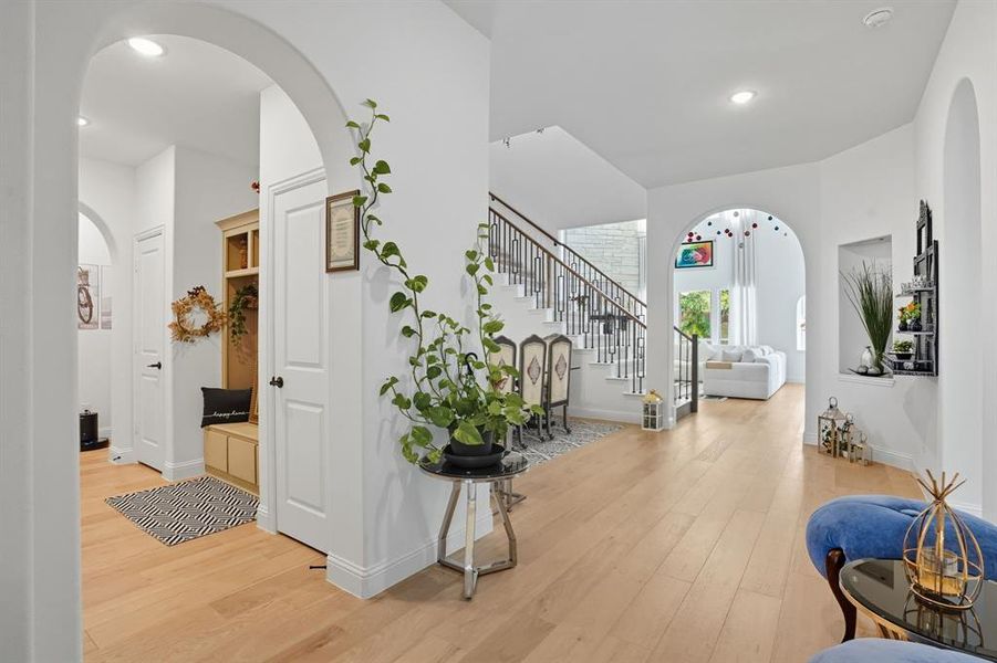 Hall featuring arched walkways, light wood-style floors, recessed lighting, and stairway
