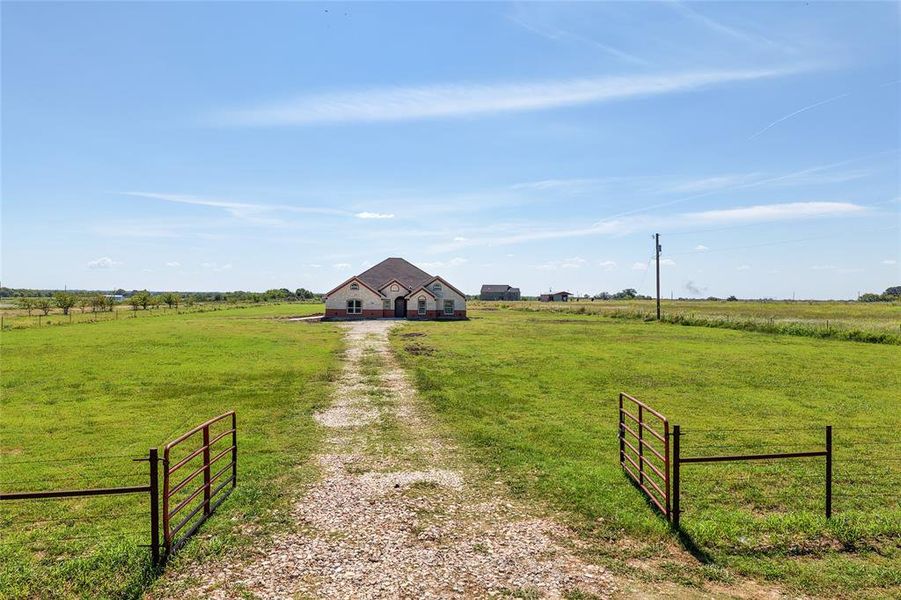 View of dirt / gravel road featuring a rural view and a gated entry