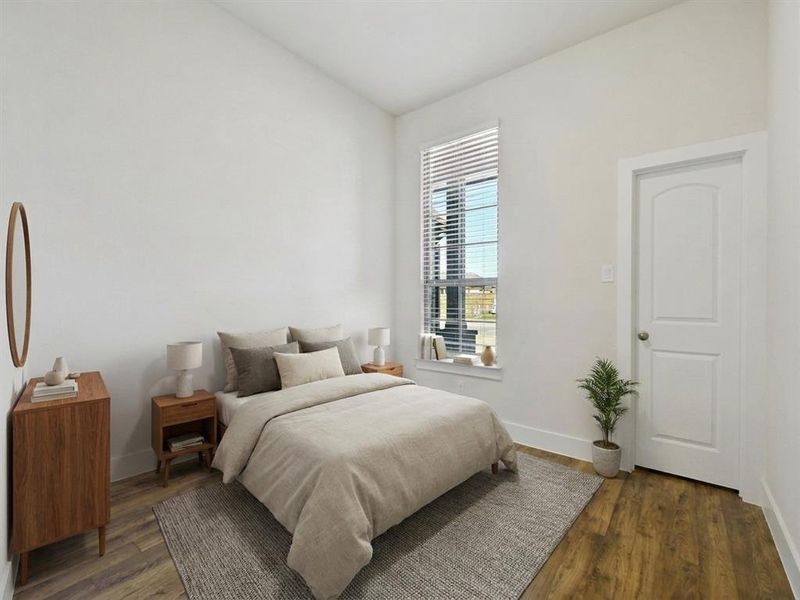 Interior room featuring wood-finish flooring, white walls, and a white arched panel door