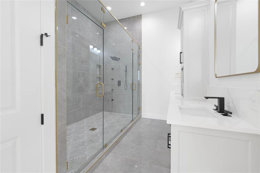 Full bathroom with double vanity, recessed lighting, and a shower stall