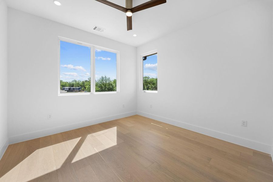 Naturally illuminated interiors boast light wood flooring and a modern ceiling fan, creating an inviting atmosphere.