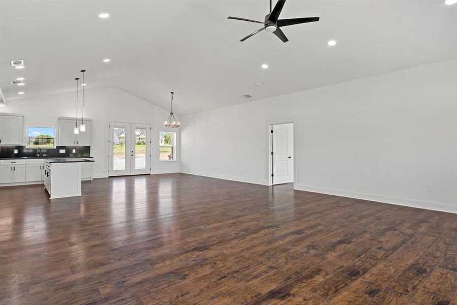 Unfurnished living room featuring high vaulted ceiling, french doors, ceiling fan, and wood-type flooring