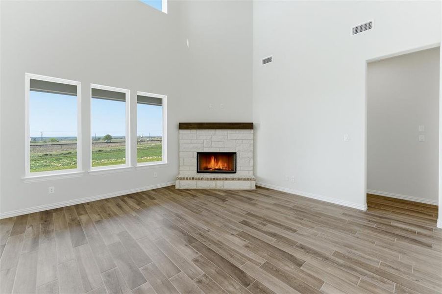 Unfurnished living room with wood tiled floors, a fireplace, and a high ceiling Unfurnished living room with wood tiled floors, a fireplace, and a high ceiling