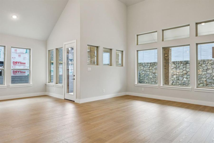 Spare room featuring light wood-style flooring, healthy amount of natural light, high vaulted ceiling, and recessed lighting