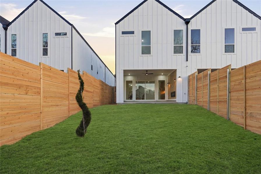 Rear view of property with board and batten siding, a fenced backyard, and a patio